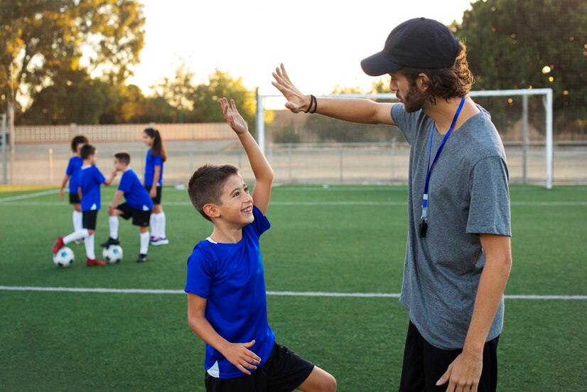 football-trainer-congratulating-child-side-view